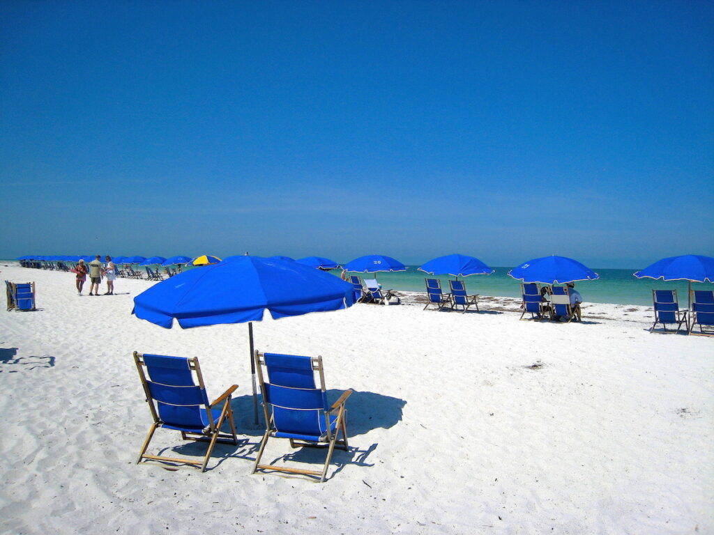 weißer Strand und blaue Schirme
