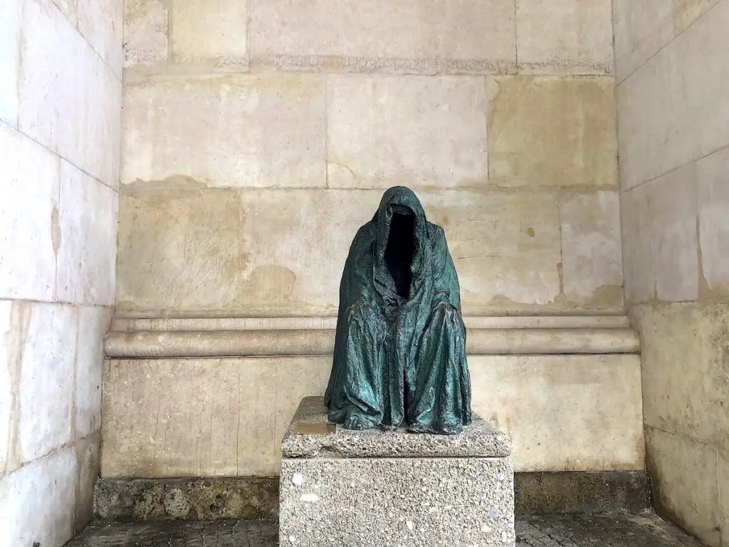Unheimliche Orte beim Citytrip nach Salzburg entdecken - die "Pietá" genannte Skulptur hockt am Dom 